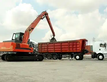 large excavator putting recyclable items in a trailer