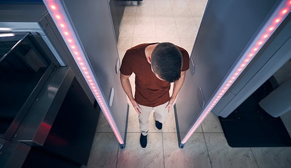 red lights flash as a citizen walks through a metal detector