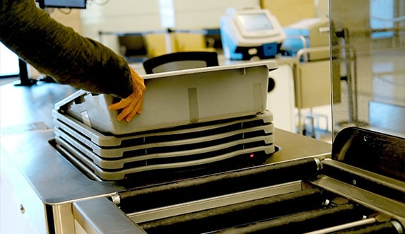 traveler stacking their bin at the security gate