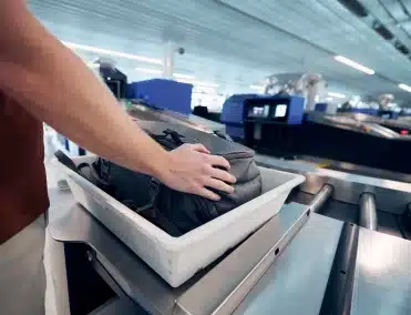 person picking up back from a bag scan conveyor